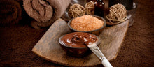 Cargar imagen en el visor de la galería, Photo of chocolate pudding style massage butter in a dish with a paint brush applicator next to a bowl of brown sugar with a rolled towel in the background. Photo from a stock internet photo and does not represent product advertised.